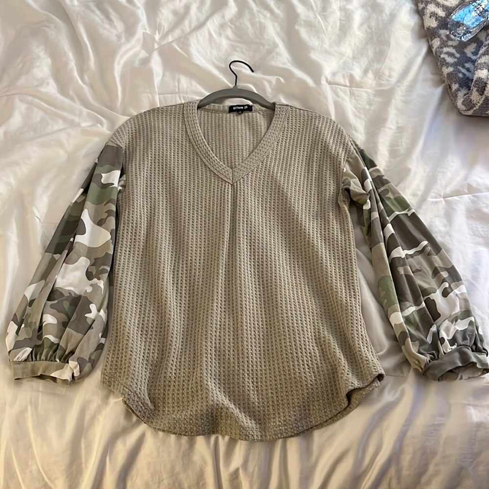 A dark tan long sleeve shirt with camp detailing. and V neckline.